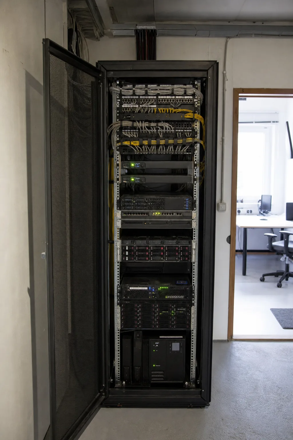 Offener Serverschrank mit Patchpanels, gebündelten Netzwerkkabeln und Statusleuchten.
